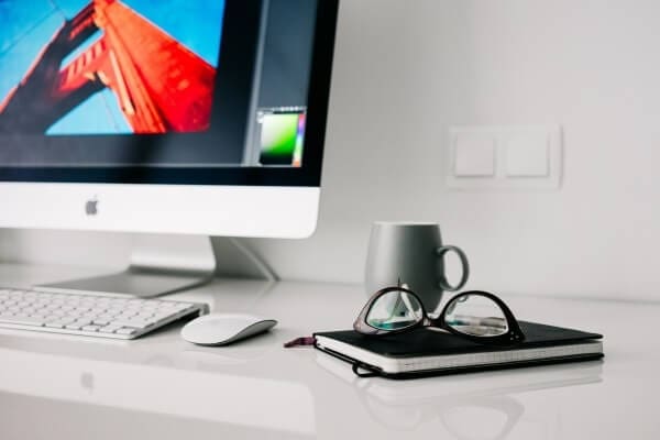 computer on table with mug eyeglasses and diary on table