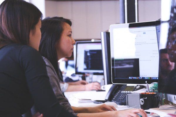 female colleagues working on computer sitting at office desk