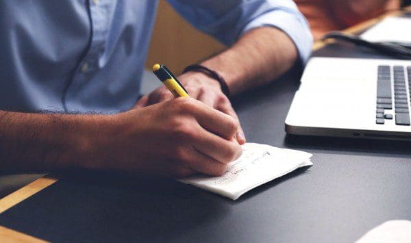 man writing in notebook