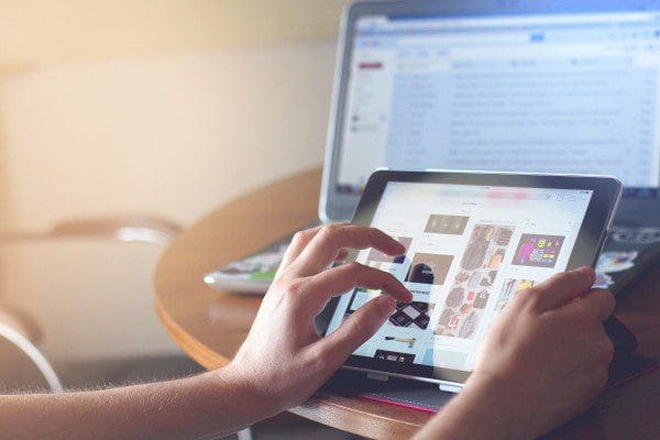 woman using digital tablet with laptop in background