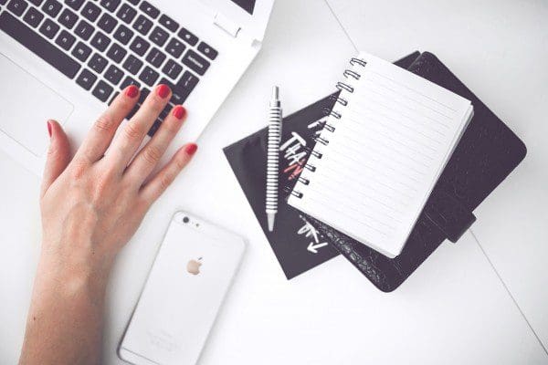 woman working on laptop with notebook and mobile phone on table